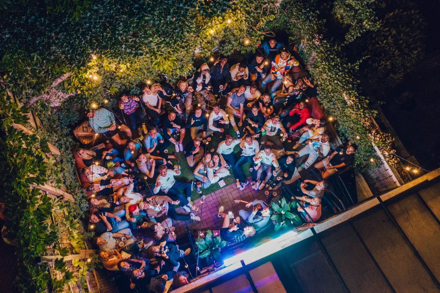 Aerial night photograph of Reneé Rapp’s private concert in New York’s West Village, the courtyard crowd gathered under strings of warm bulb lights
